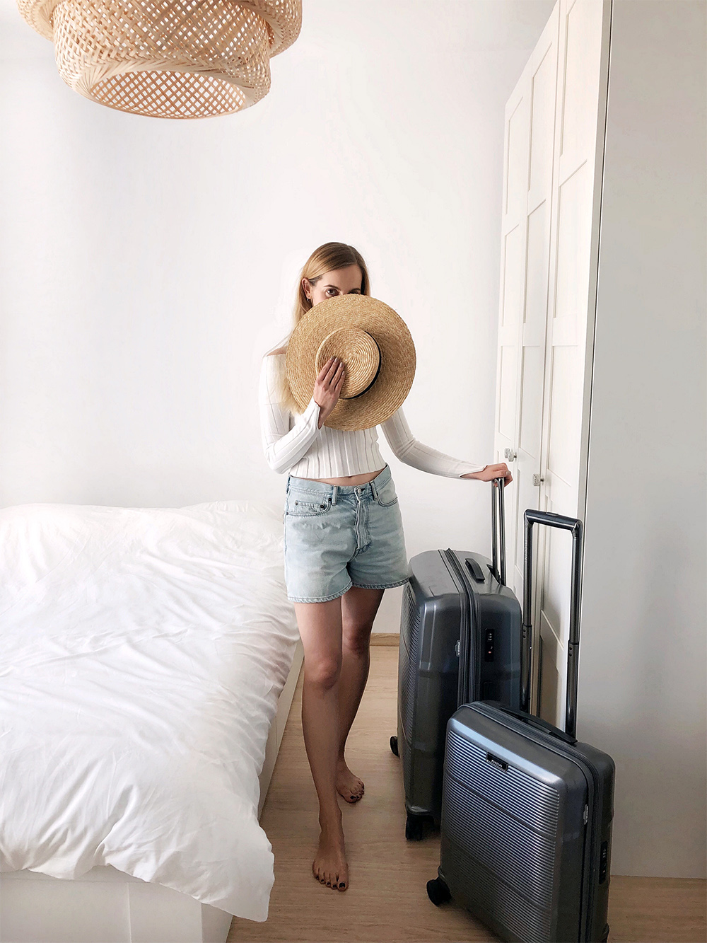 Girl with straw hat and suitcases. Holiday packing
