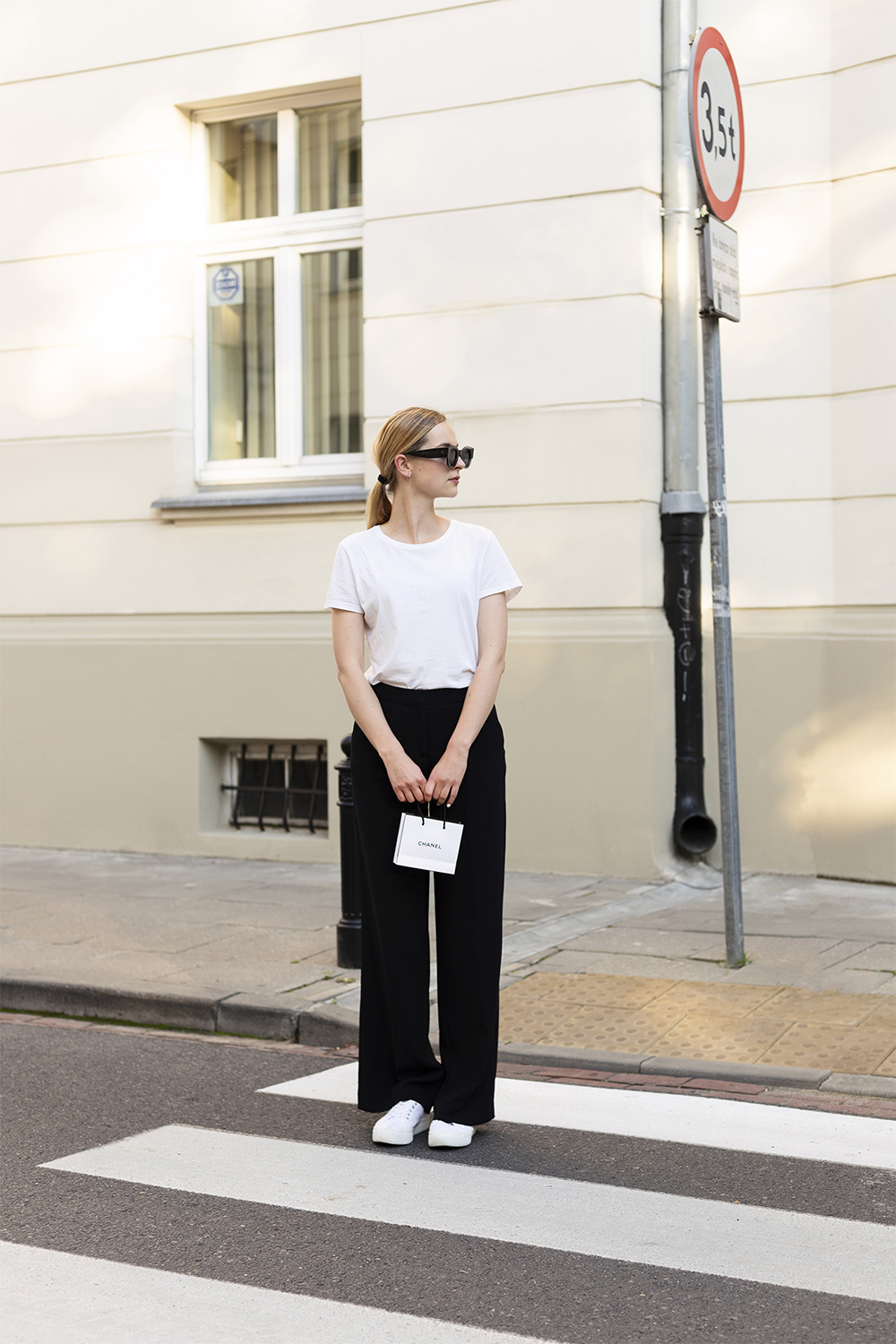 Girl in white t-shirt and black palazzo pants with Chanel makeup bag